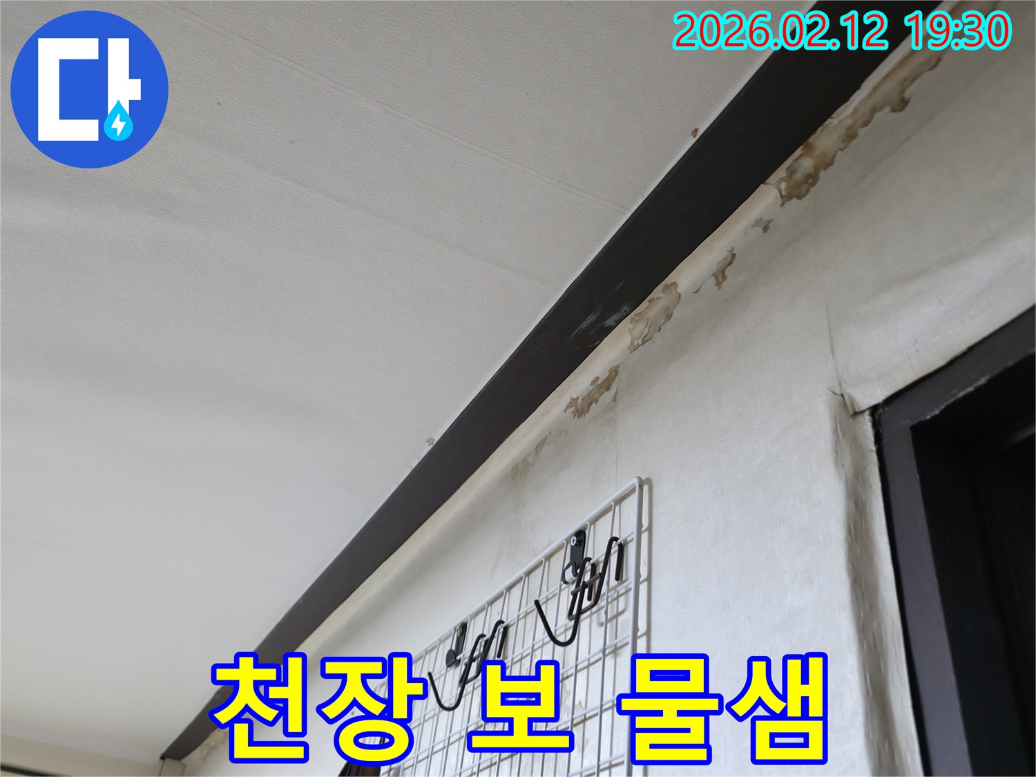 천장-아래-보-부분과-벽면-경계에서-물이-새어-나와-벽지가-손상된-모습을-보여주는-사진