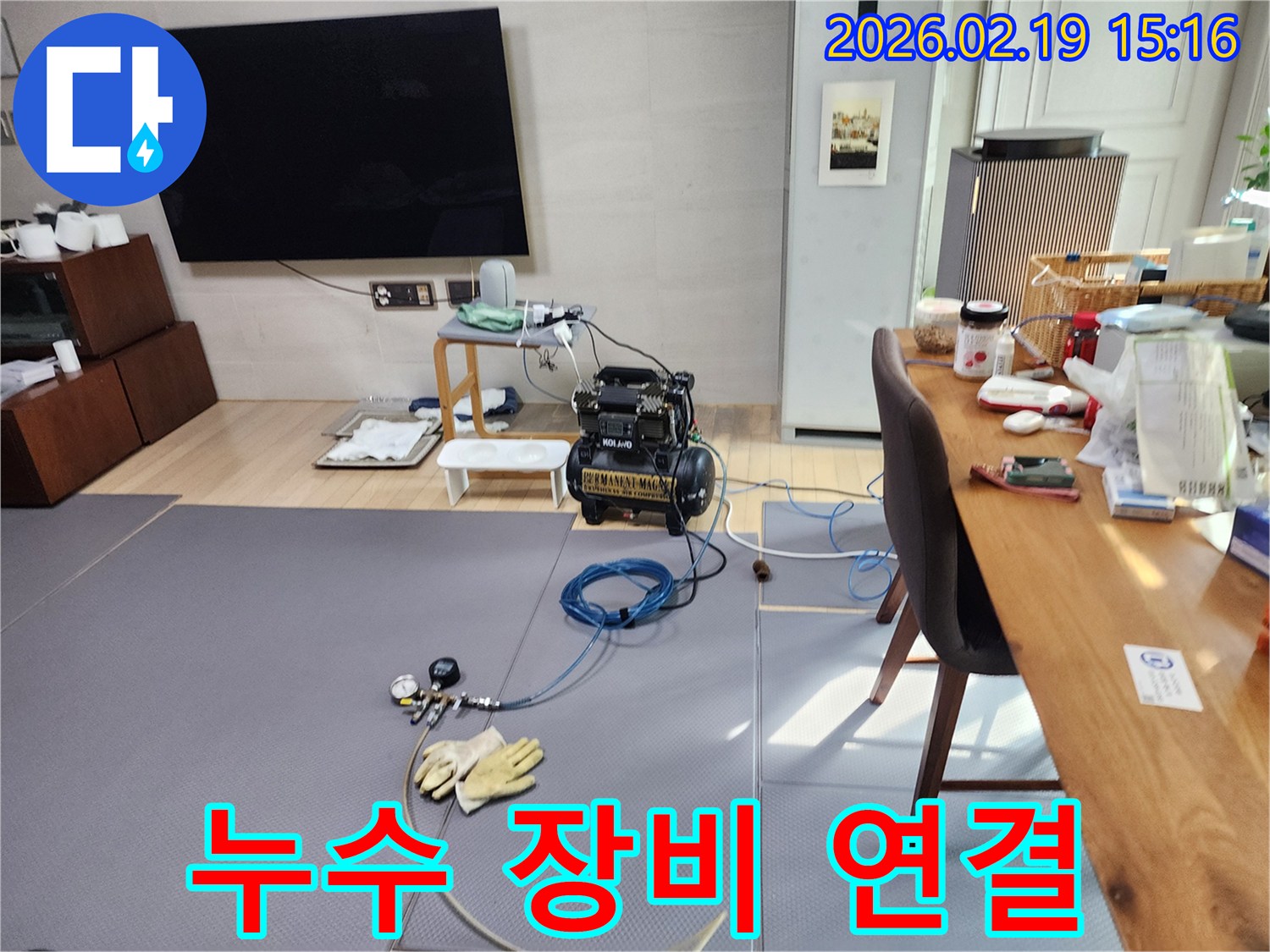 아파트 내부에서 누수 탐지 장비를 배관에 연결하고 있는 현장 모습입니다.