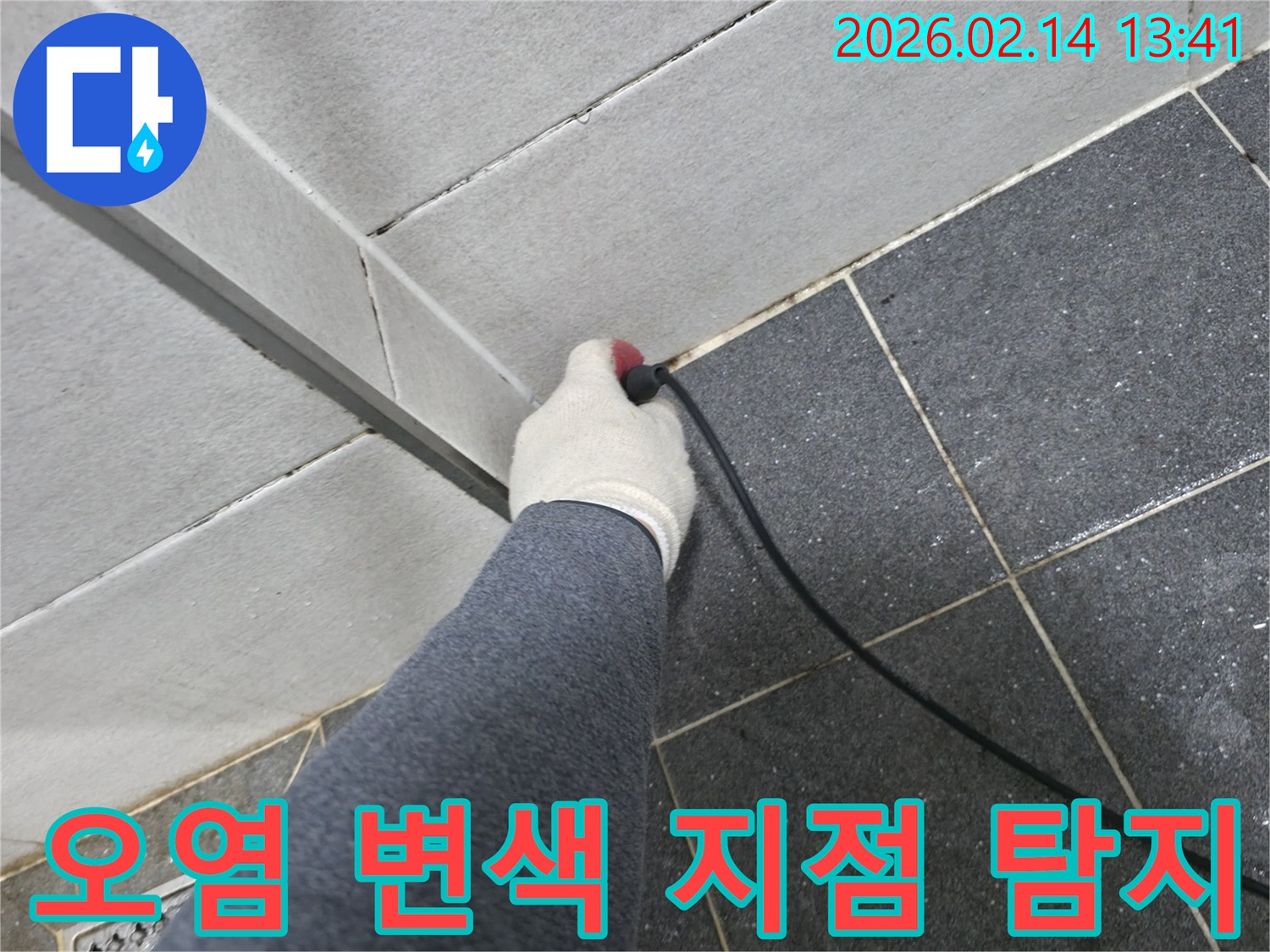 누수 엔지니어가-작업 장갑을 착용하고-누수 탐지 장비로-타일 틈새의 오염 및 변색 지점을-정밀하게 탐지하는 장면입니다.
