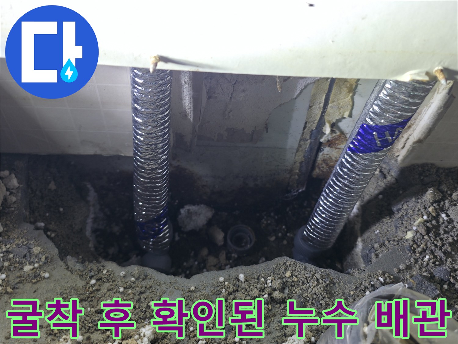 싱크대 아래 흙을 파내어 드러난 은색 주름관과 물기 있는 지점 사진