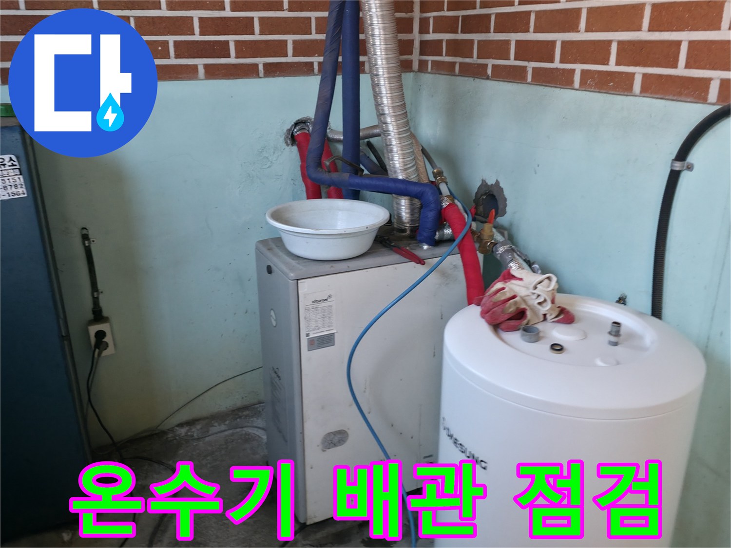 하얀색 온수기와 벽면 붉은 벽돌 사이의 배관 연결 상태를 보여줍니다.