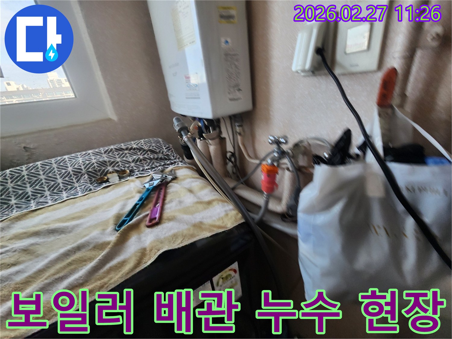 세탁실 보일러 아래 배관에서 발생한 누수를-전문가가 탐지하고 수리하는 모습입니다