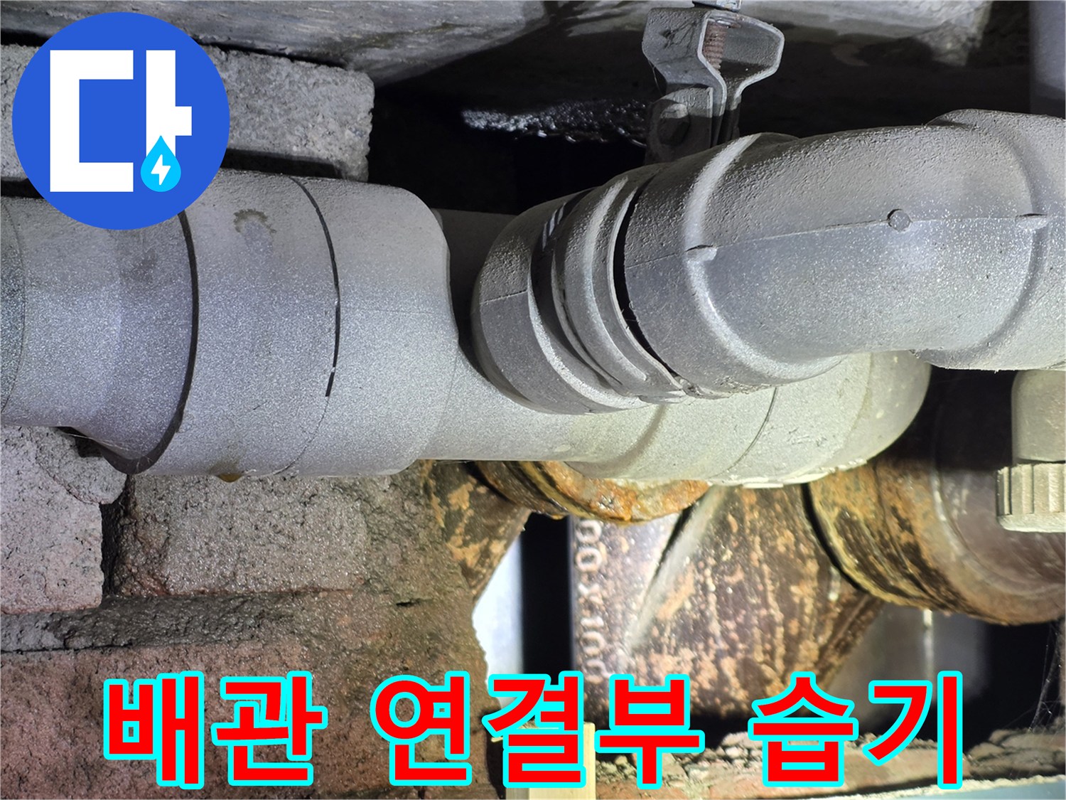 배관 연결 부위 주변의 젖은 흔적과 부식된 금속 부품