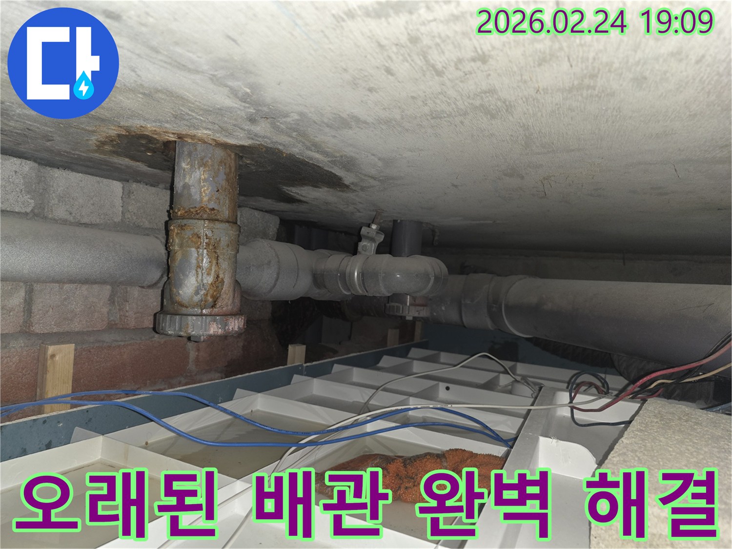 오래된 배관에서 물이 새어 나와 임시 물받이에 고인 물과 함께 보이는 현장