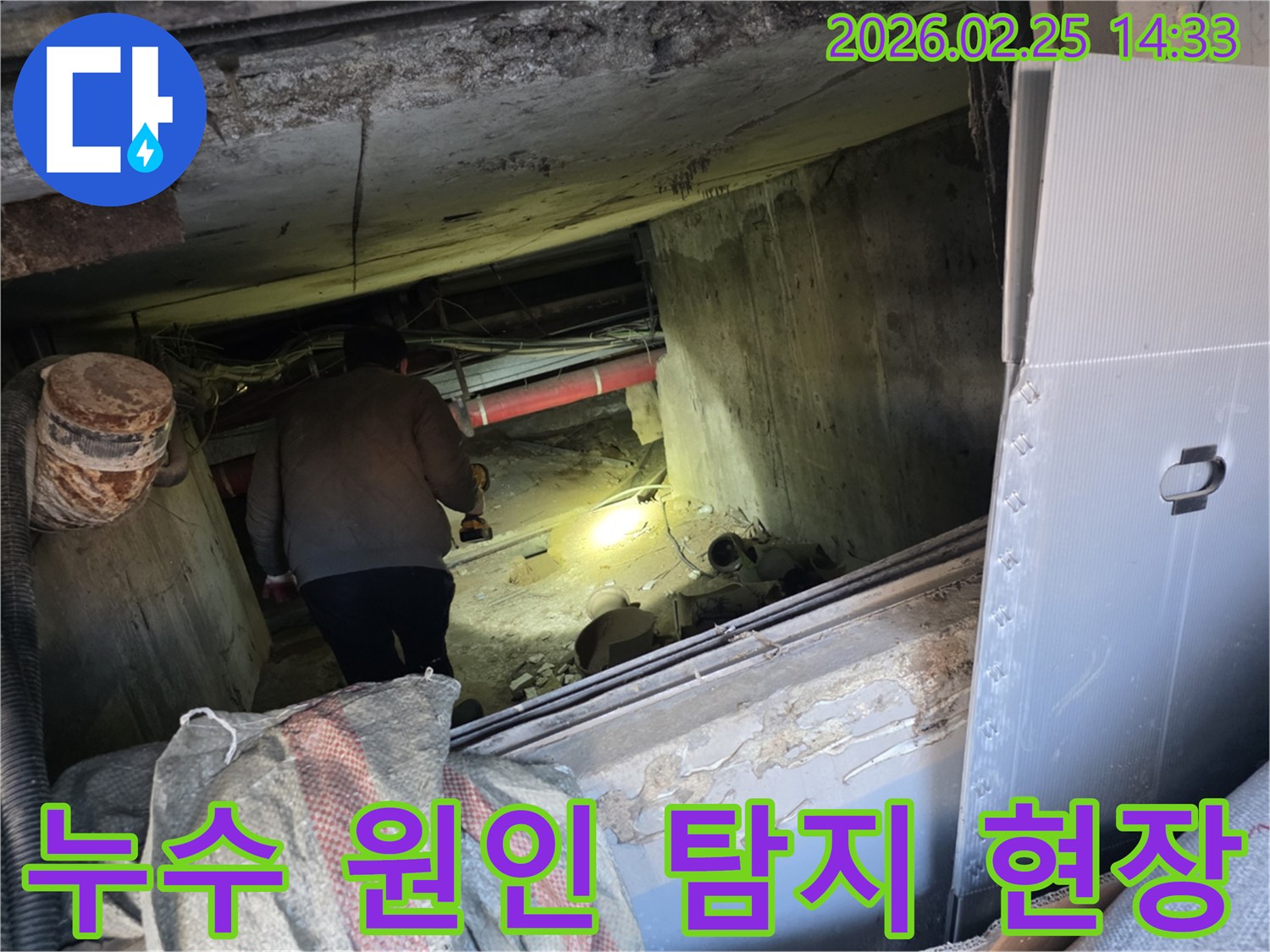 누수 전문 엔지니어가-손전등을 사용하여-어둡고 좁은 공간에서-배관의 누수 흔적을-세밀하게 탐지하는 모습입니다.