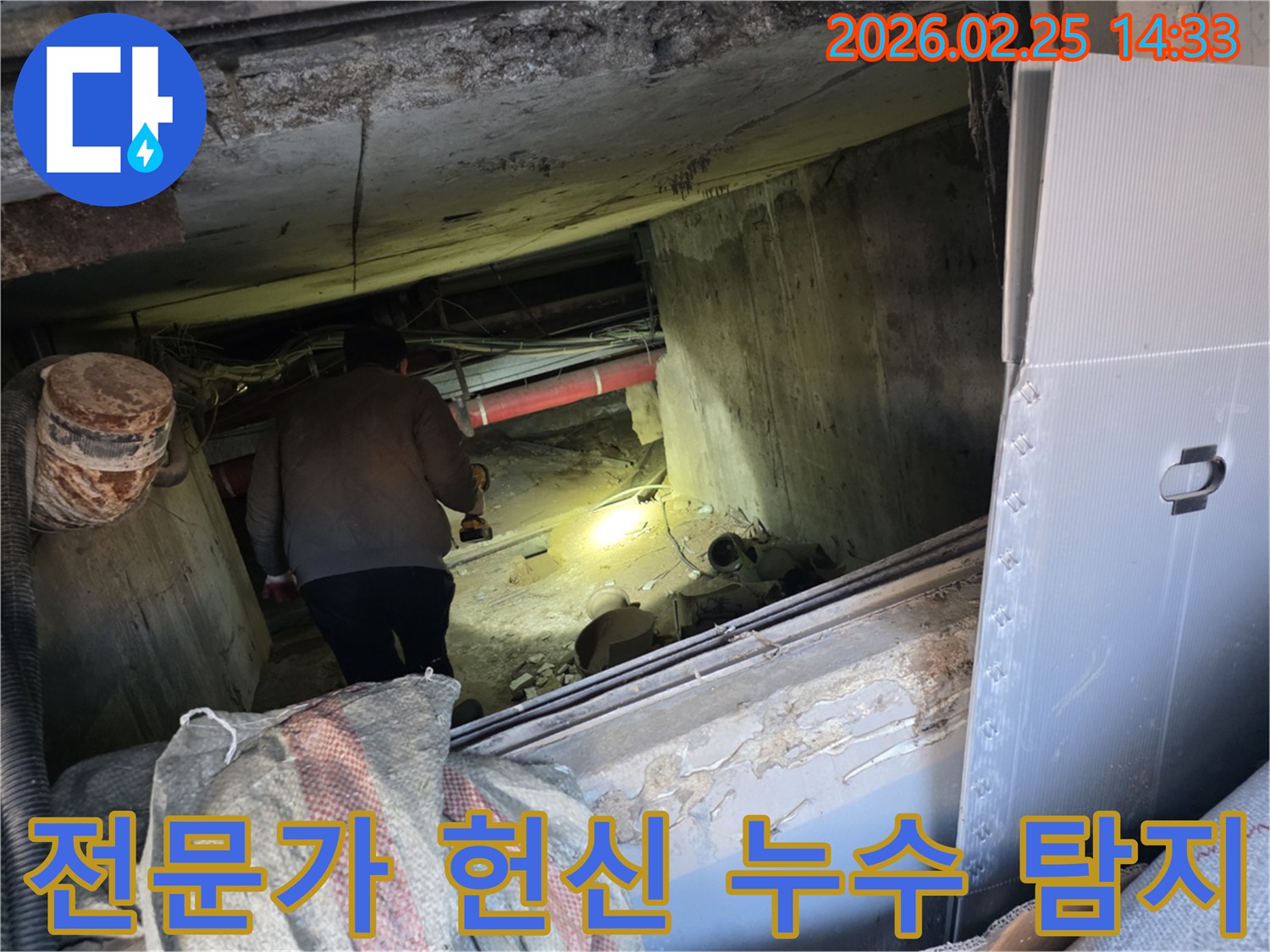 누수 전문 엔지니어가-어둡고 좁은 공간에서-손전등을 비춰가며-고객의 불편을 해소하기 위해-헌신적으로 누수 지점을-탐지하는 모습입니다.