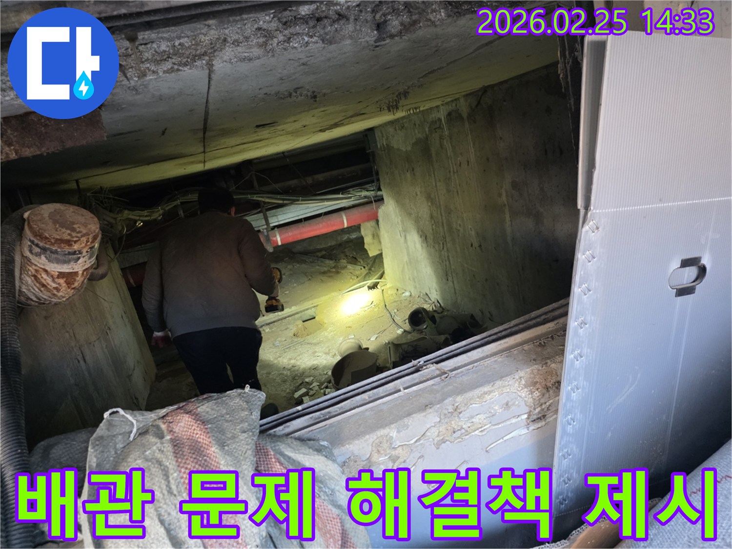 누수 전문 엔지니어가-어둡고 좁은 공간에서-손전등을 비춰가며-배관 문제의 정확한 원인을-찾아내어 해결책을 제시하는 모습입니다.