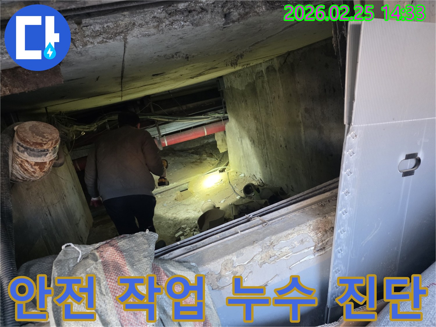 누수 전문 엔지니어가-어둡고 좁은 공간에서-안전 수칙을 준수하며-손전등을 비춰가며-누수 지점을 정확히-진단하는 모습입니다.