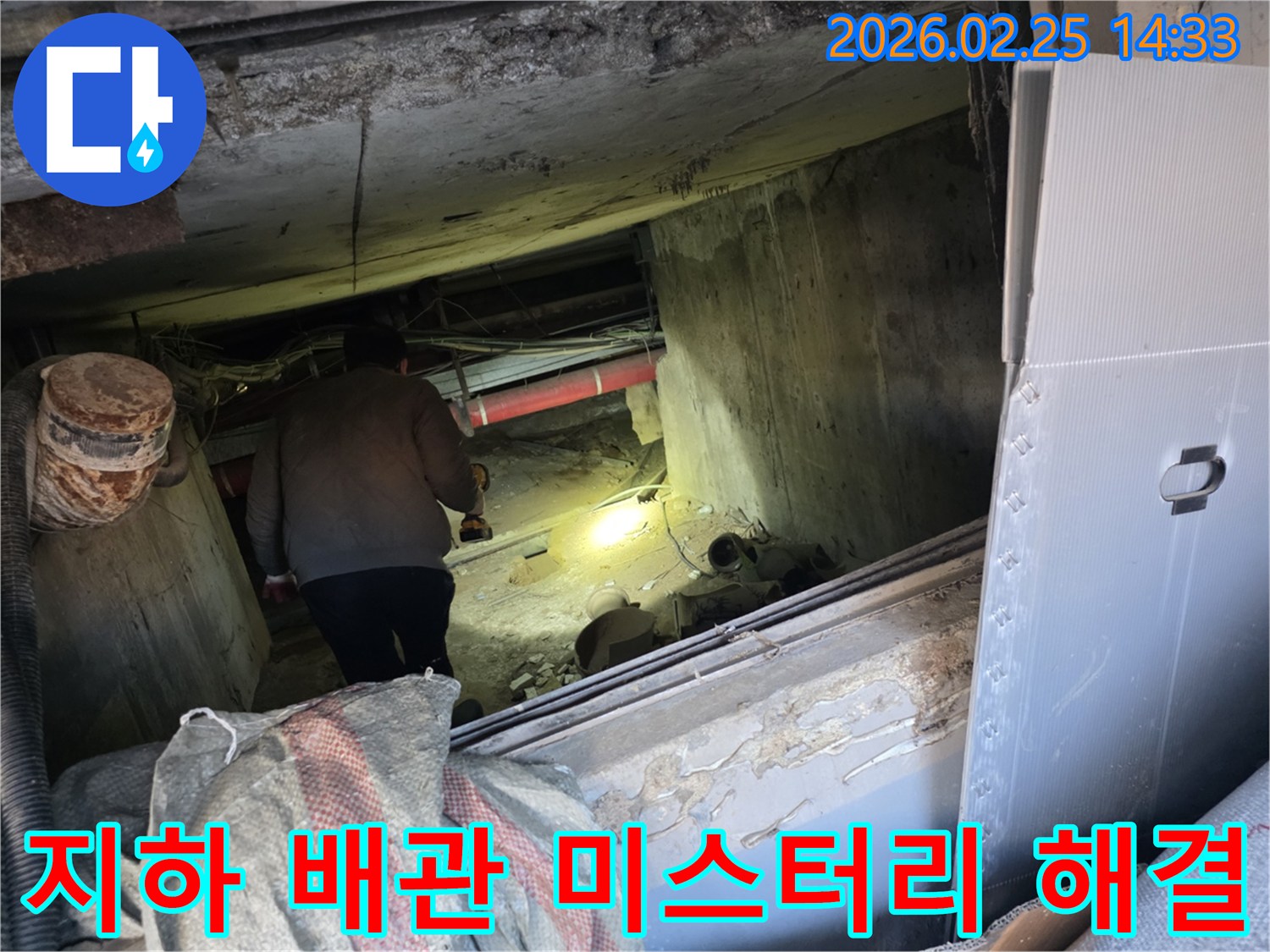 누수 전문 엔지니어가-어둡고 좁은 지하 공간에서-손전등을 비춰가며-배관의 숨겨진 누수 지점을-정밀하게 탐색하여-미스터리를 해결하는 모습입니다.