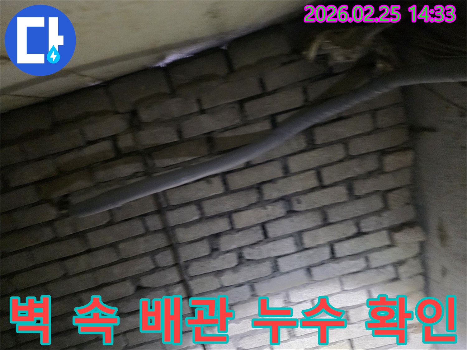 어두운 벽돌 벽면을 배경으로-단열된 배관과 함께-누수 여부를 확인하기 위해-정밀하게 검사되는 현장 모습입니다.