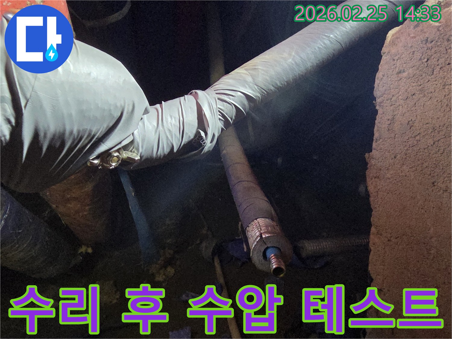 어두운 작업 공간에서-장갑을 낀 손이-누수 수리된 배관에-수압을 가하여-누수 여부를-최종적으로 확인하는-모습입니다