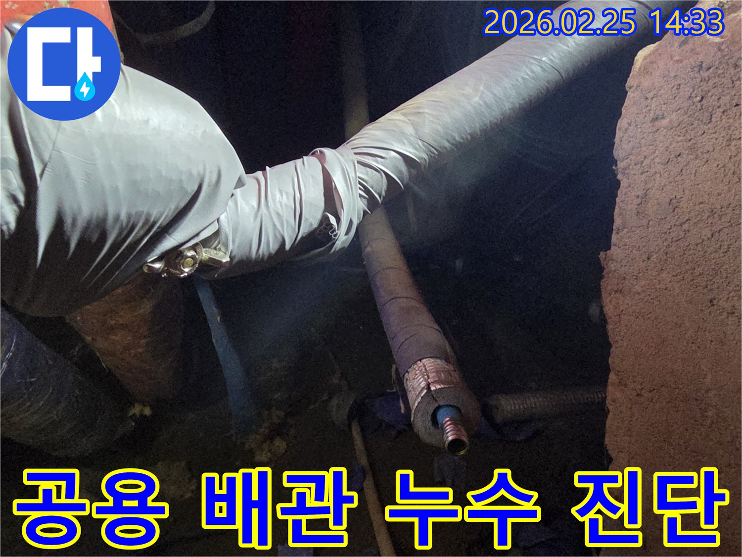 어두운 작업 공간에서-장갑을 낀 손이-다세대 주택의-공용 배관을-세심하게 점검하며-누수 원인을-진단하는 모습입니다