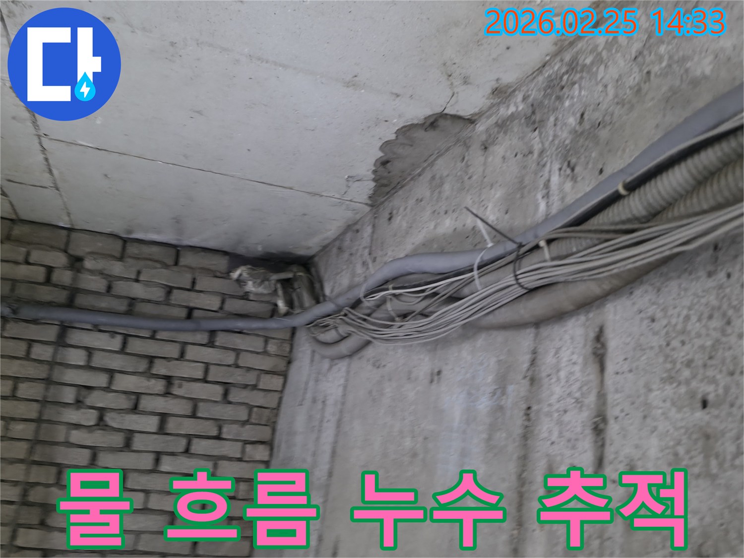 지하 벽면의-콘크리트와-벽돌 벽이 만나는-지점에서-발견된-오랜 누수로 인한-물자국과-주변의 복잡한 배관
