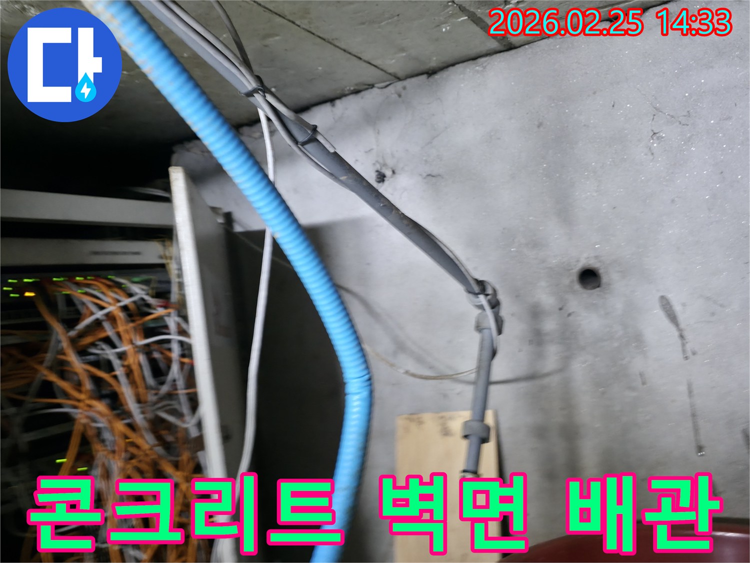 콘크리트 벽면에 고정된-파란색 주름관과 회색 케이블들이-누수 탐지 작업의-중요한 단서가 될 수 있음을-시각적으로 보여주는 현장입니다