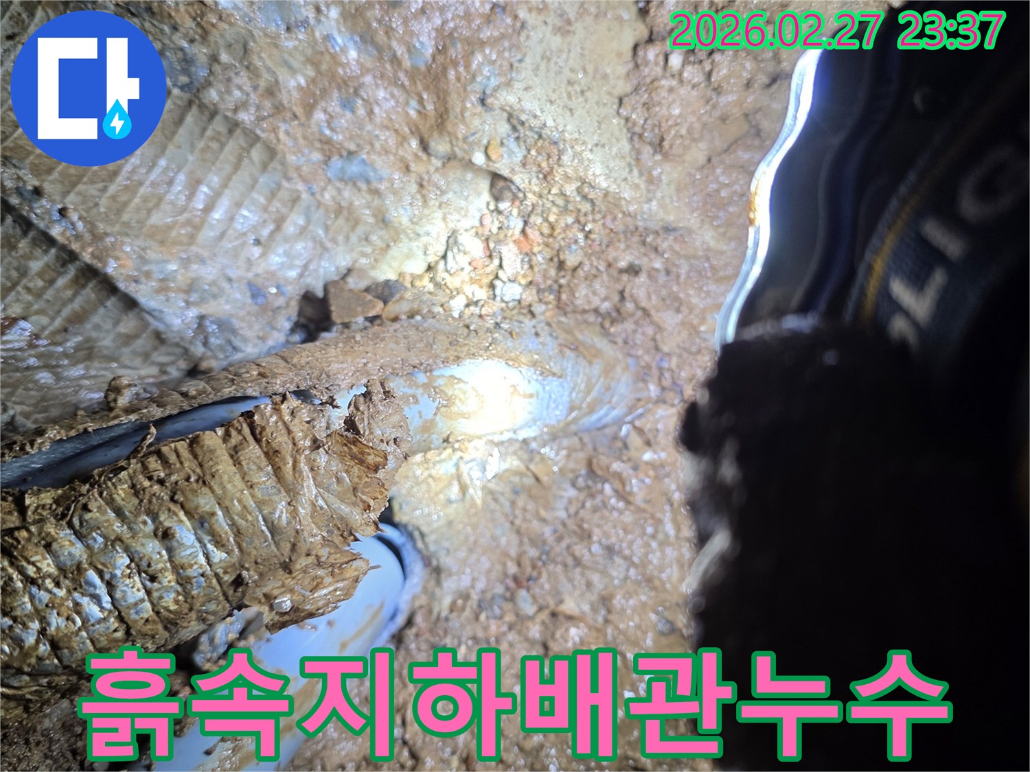 흙과-진흙으로-뒤덮인-지하-현장에서-발견된-배관의-누수-지점을-확대하여-보여주는-사진입니다