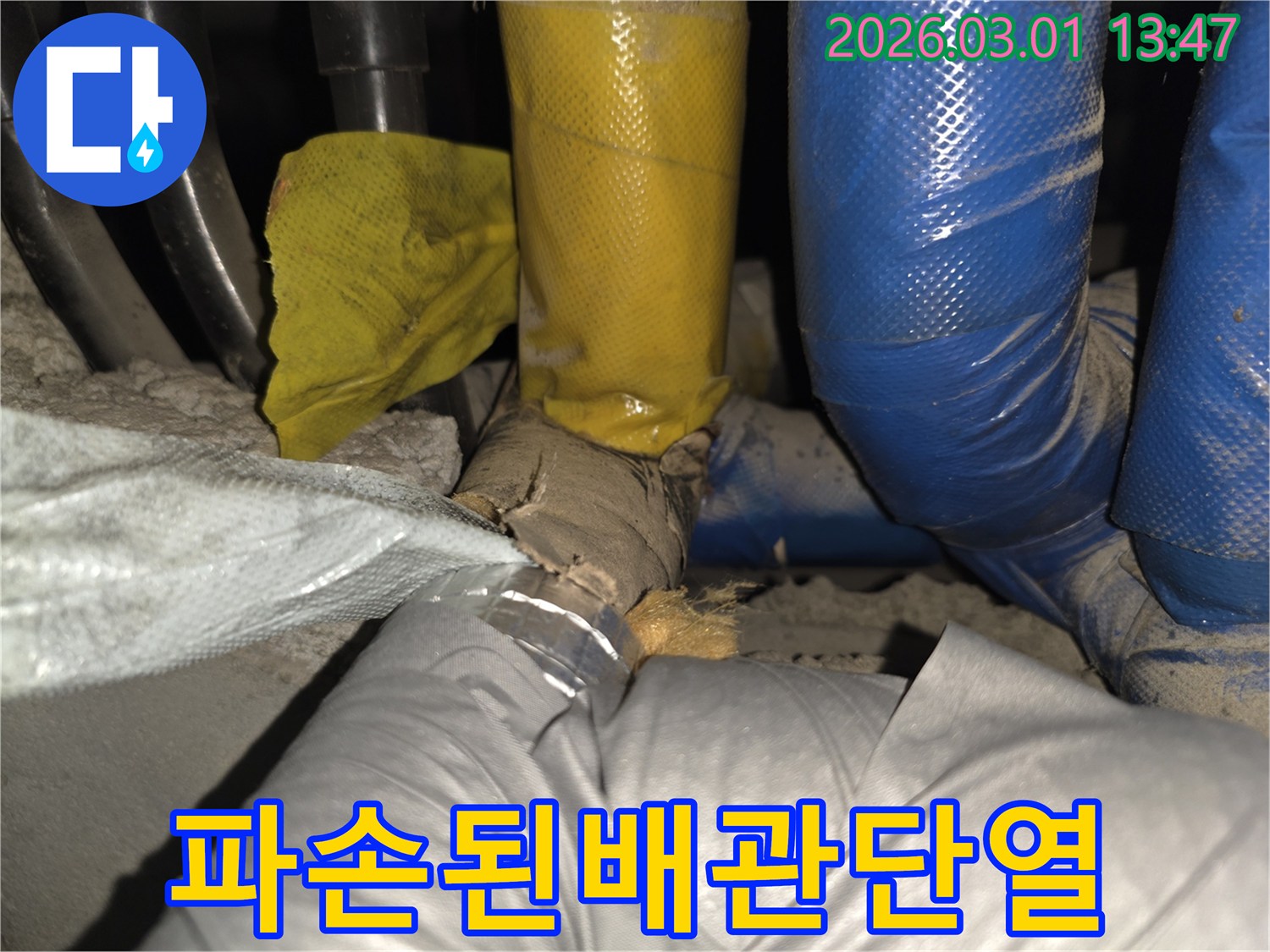 배관 주변의 보호막이 훼손되어-내부 단열재가 노출된 상태를 촬영한 사진입니다.