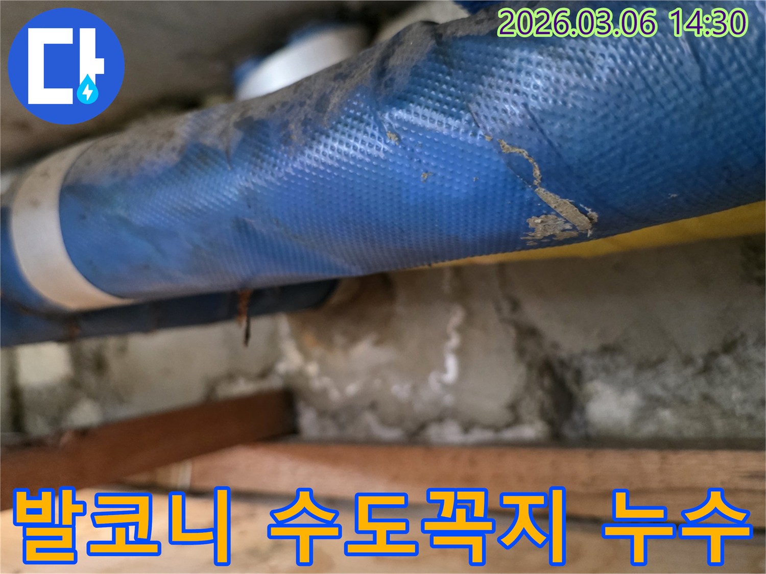 아파트 발코니 하부-파란색 수도 배관과-젖은 콘크리트 벽면-그리고 나무 지지대를-꼼꼼히 점검하는 모습