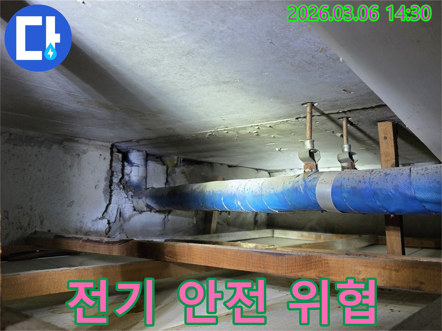 지하 공간의 파란색 배관 주변-누수로 인해 습기가 찬-콘크리트 벽면을-누수 엔지니어가-전기 안전 위협 요소를-점검하며 진단하는 모습