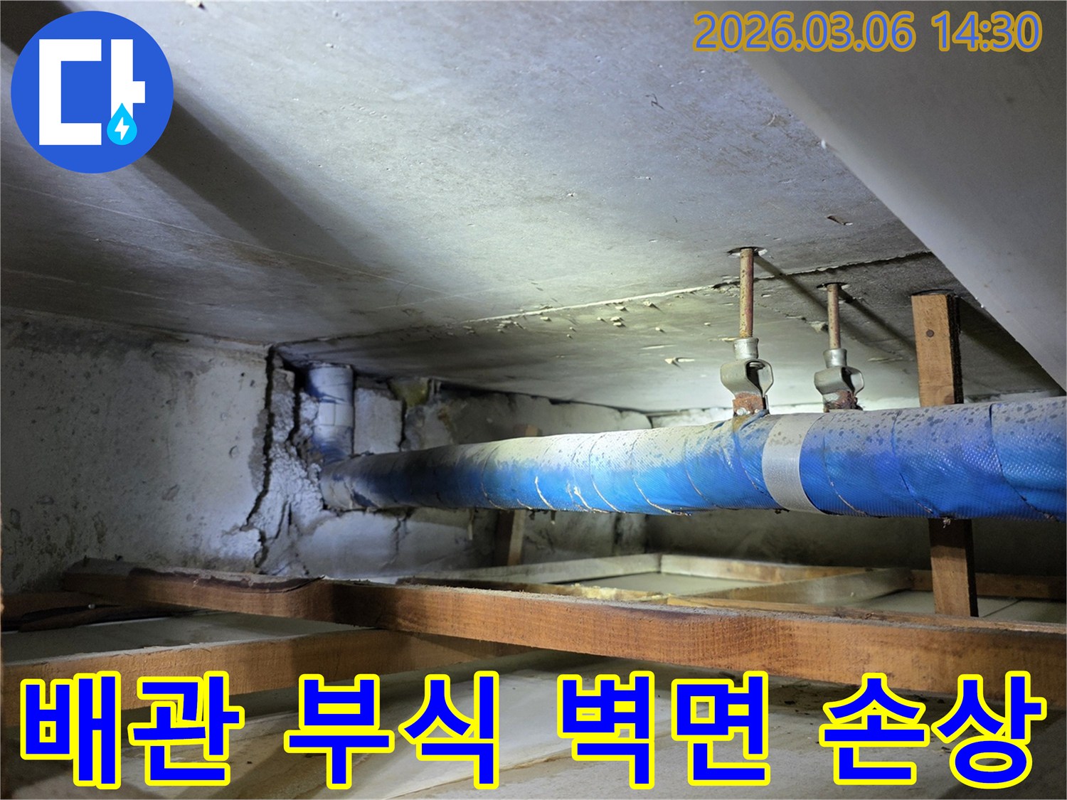 지하 공간의 파란색 배관에서-부식으로 인해 누수가 발생하여-콘크리트 벽면이 손상된-현장 사진