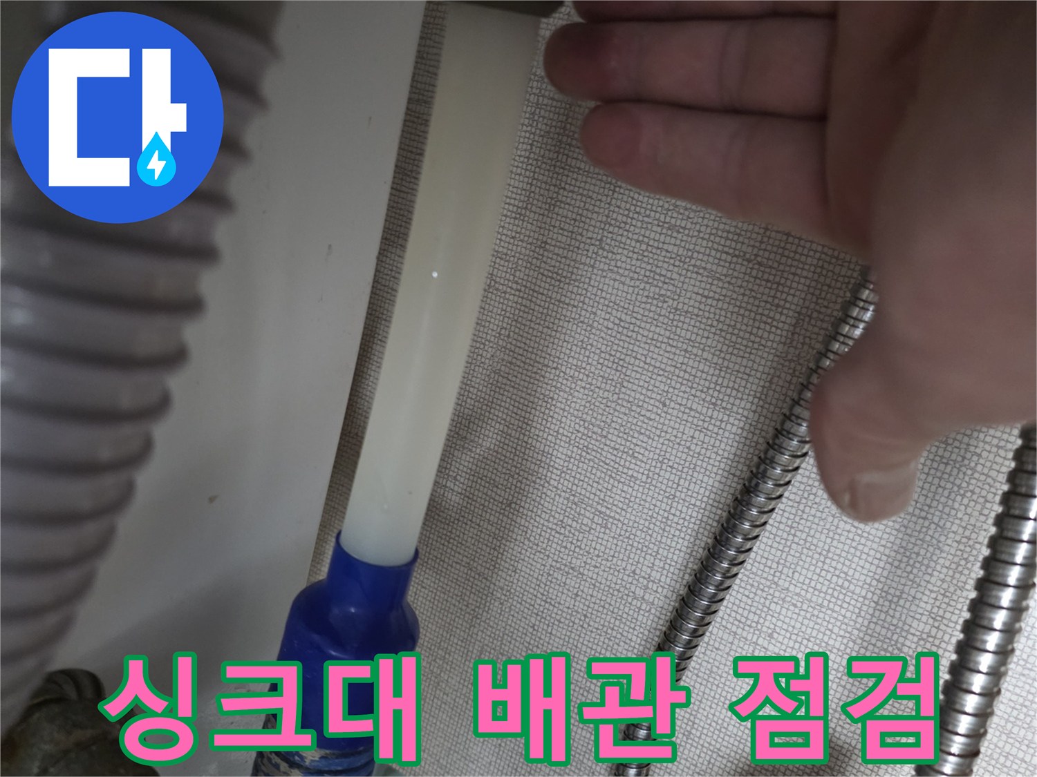 싱크대 하부의 흰색 정수기 호스와 파란색 배관 연결 부위 상세 사진
