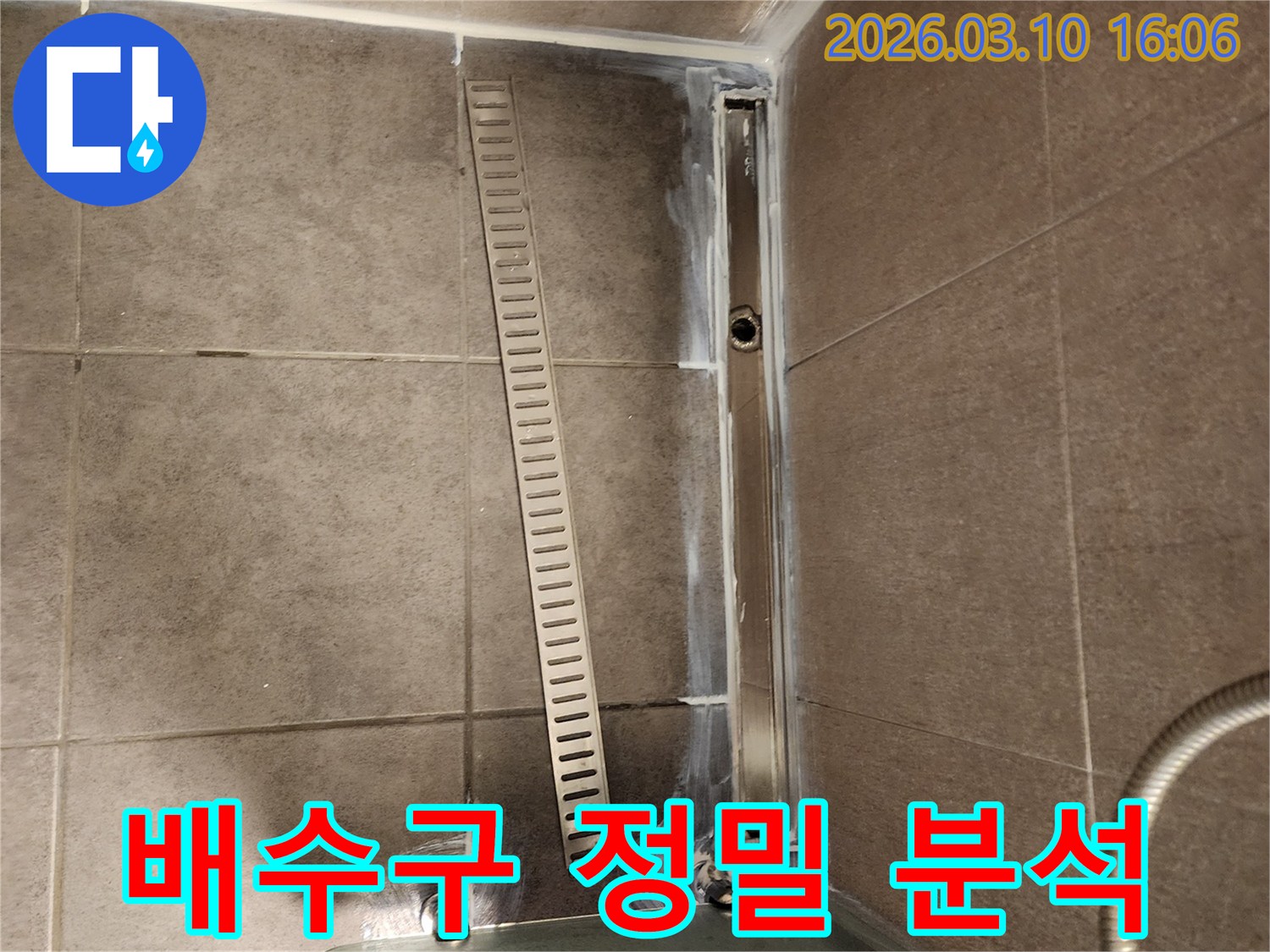 샤워실 바닥의 선형 배수구-주변의 미세한 누수 지점을 찾아내기 위해-정밀 분석 장비를 활용하는 모습입니다