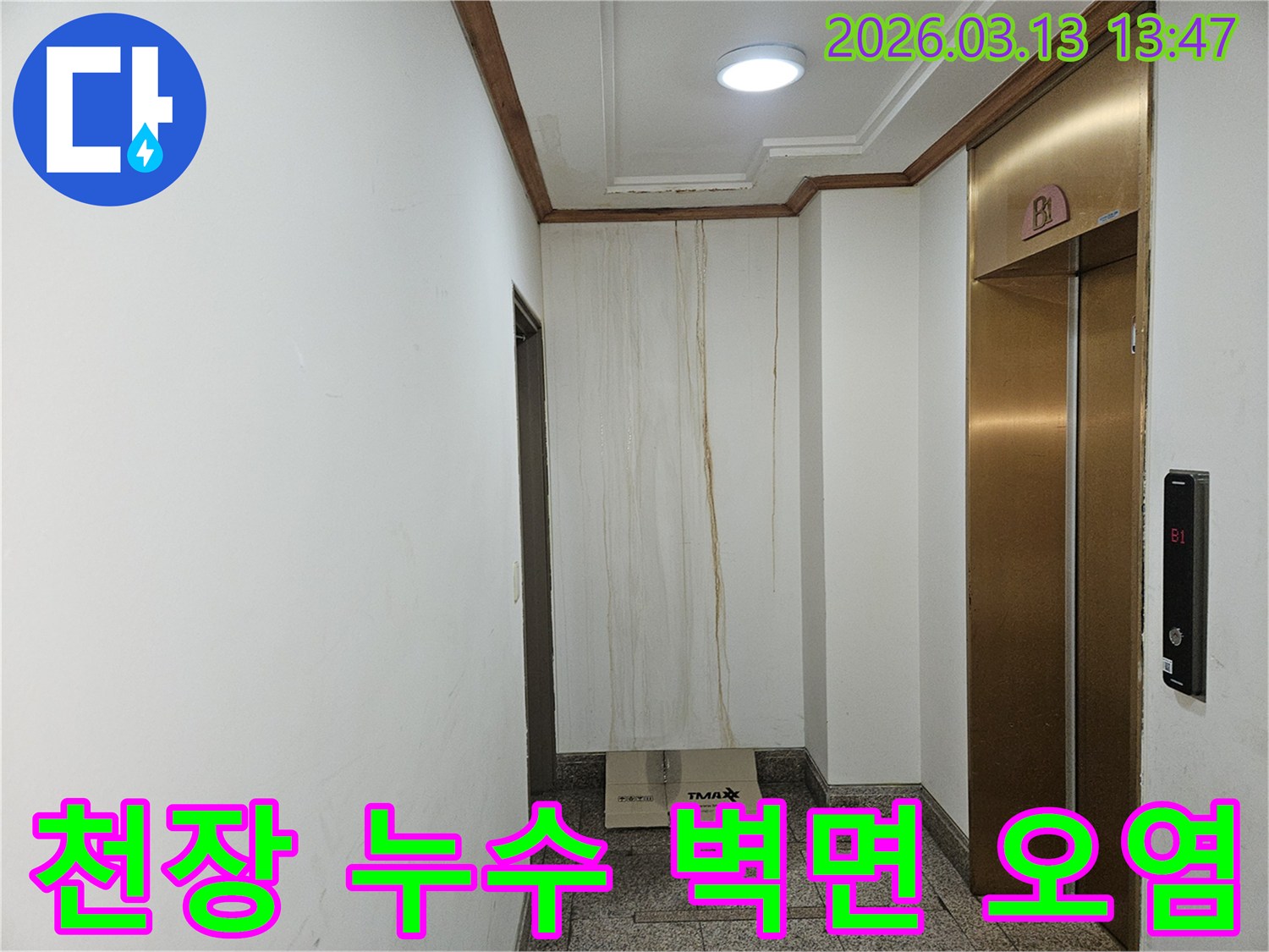 이 사진은 천장에서 시작된 누수로 인해-복도 벽면이 심하게 오염된 상황을 보여줍니다-물이 흘러내린 자국이 선명합니다
