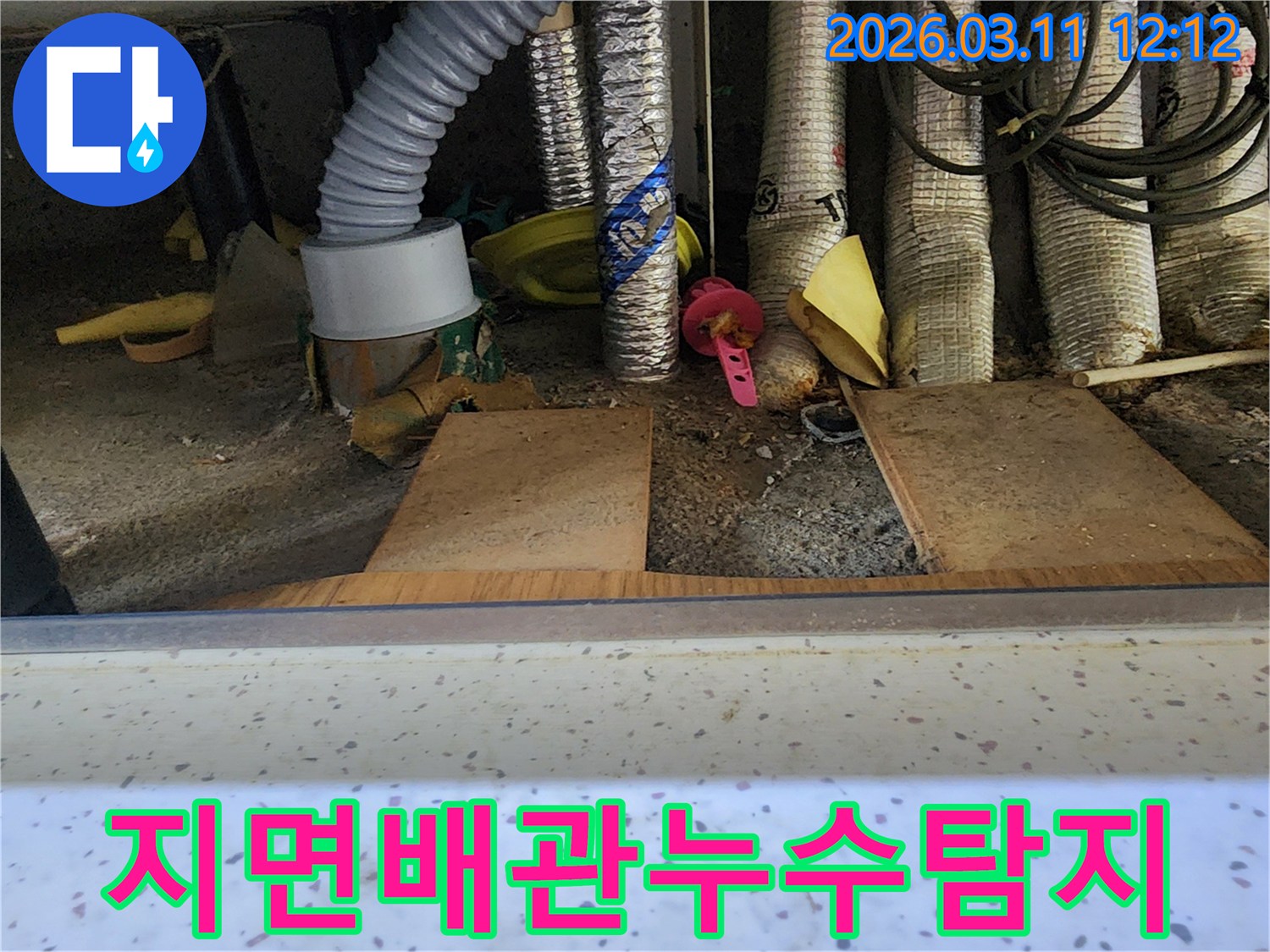 지면에-가깝게-설치된-배관-주변에서-누수-원인을-찾기-위해-전문가가-정밀하게-탐지하는-모습을-담은-사진입니다