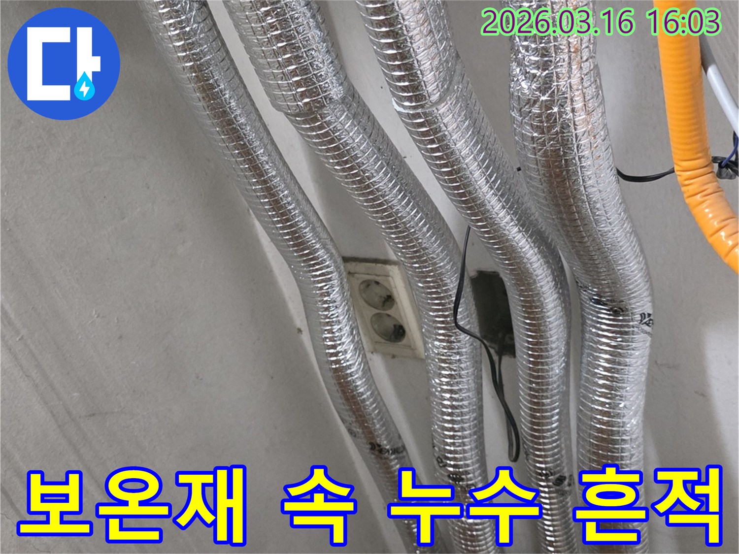 누수 탐지 전문가가-은색 보온재로 감싸진-천장 배관에서-숨겨진 누수 흔적을-찾아내는 모습입니다.
