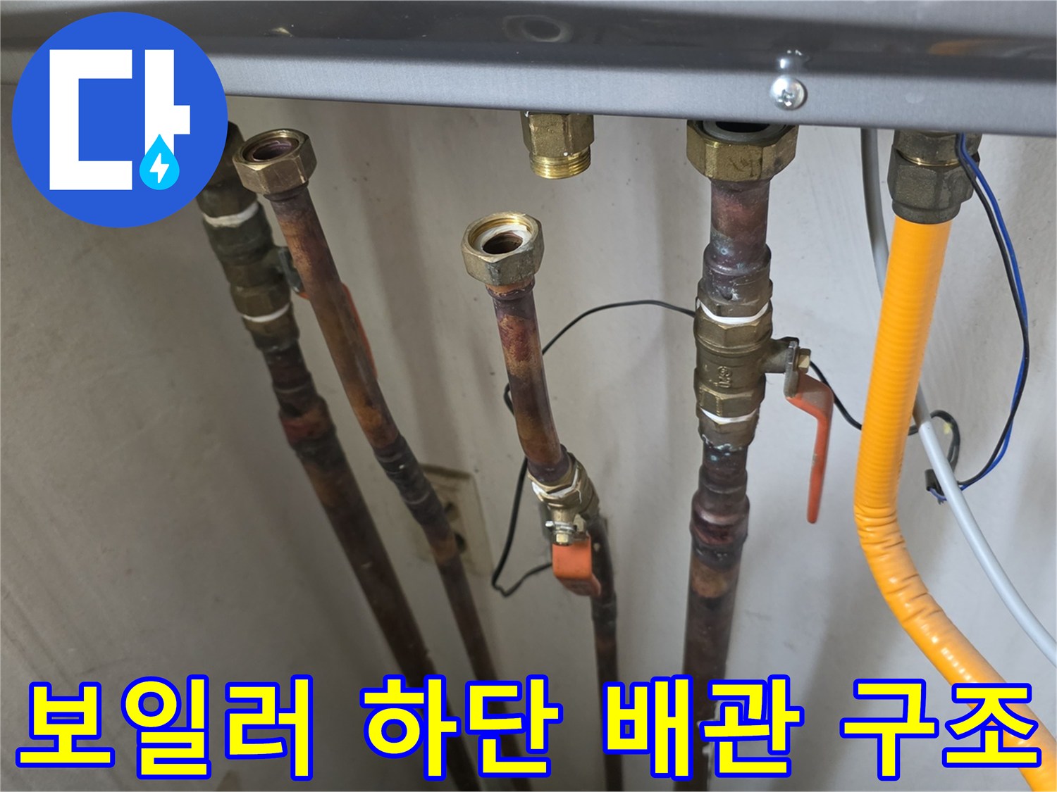 보일러 아래로 뻗어 나온 여러 개의 급수 및 온수 배관