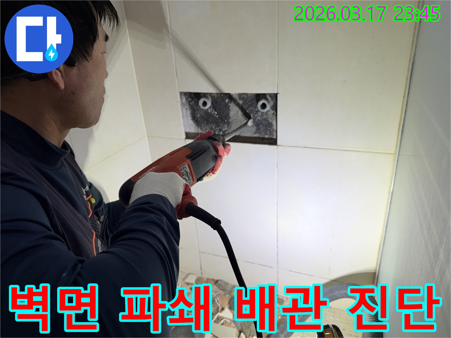 숙련된 기술자가 아파트 누수 지점을 찾아내기 위해-벽면 타일을 깨고 내부 배관을 드러내어-정밀 진단하는 작업을 진행하고 있습니다.