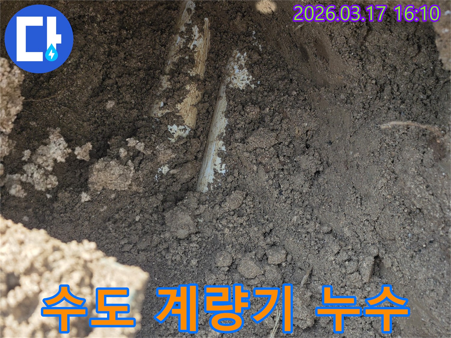 수도 계량기 주변-땅속에 묻힌 배관에서-누수가 발생하여-주변 흙이 젖어있는-모습을 보여줍니다