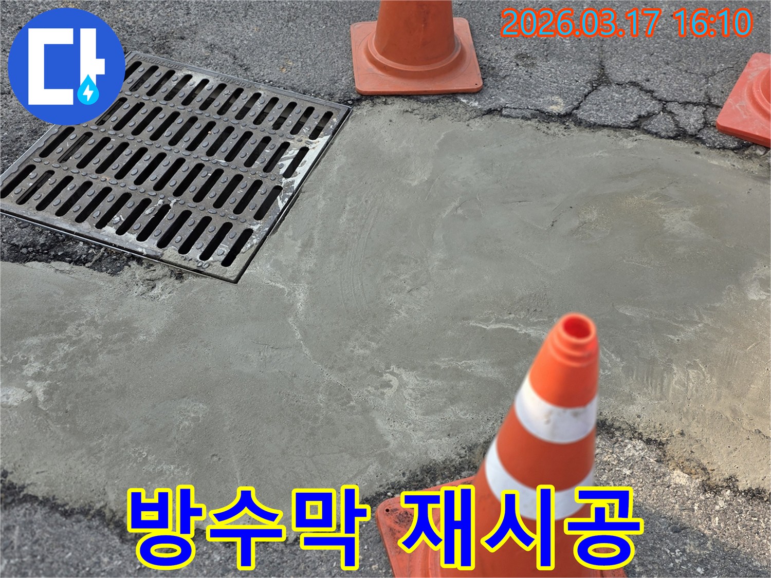 이 이미지는 양주 율정동의 빗물 누수 문제를 해결하고-배수구 주변에 방수막을 재시공한 현장을 보여주며-안전 콘이 설치되어 있습니다.