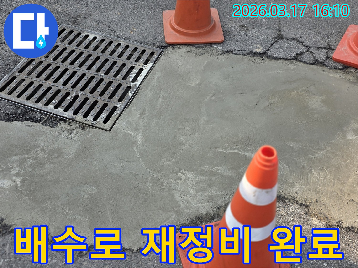 이 이미지는 양주시의 외부 배수로 누수 문제로 인한 재정비 작업이 완료된 상태를 보여주며-새로운 시멘트 마감과 안전 콘이 놓여 있습니다.
