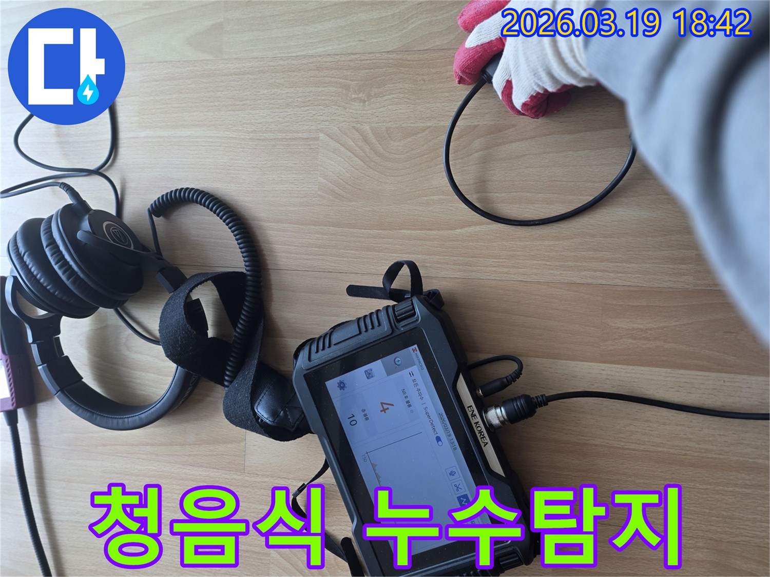 누수 탐지 전문가가-바닥에 놓인 장비와 헤드폰을 이용해-미세한 누수음을 듣고-누수 지점을 정확히 파악하는-현장 작업 모습입니다