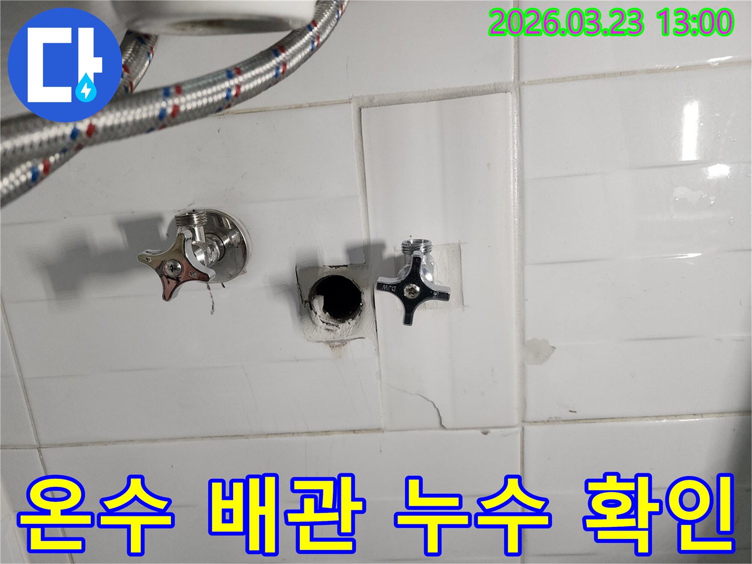 하얀색 타일 벽면의-온수 배관 연결 부위에서-누수가 확인되어-타일을 제거하고-배관을 점검하는-온수 배관 누수 현장입니다.