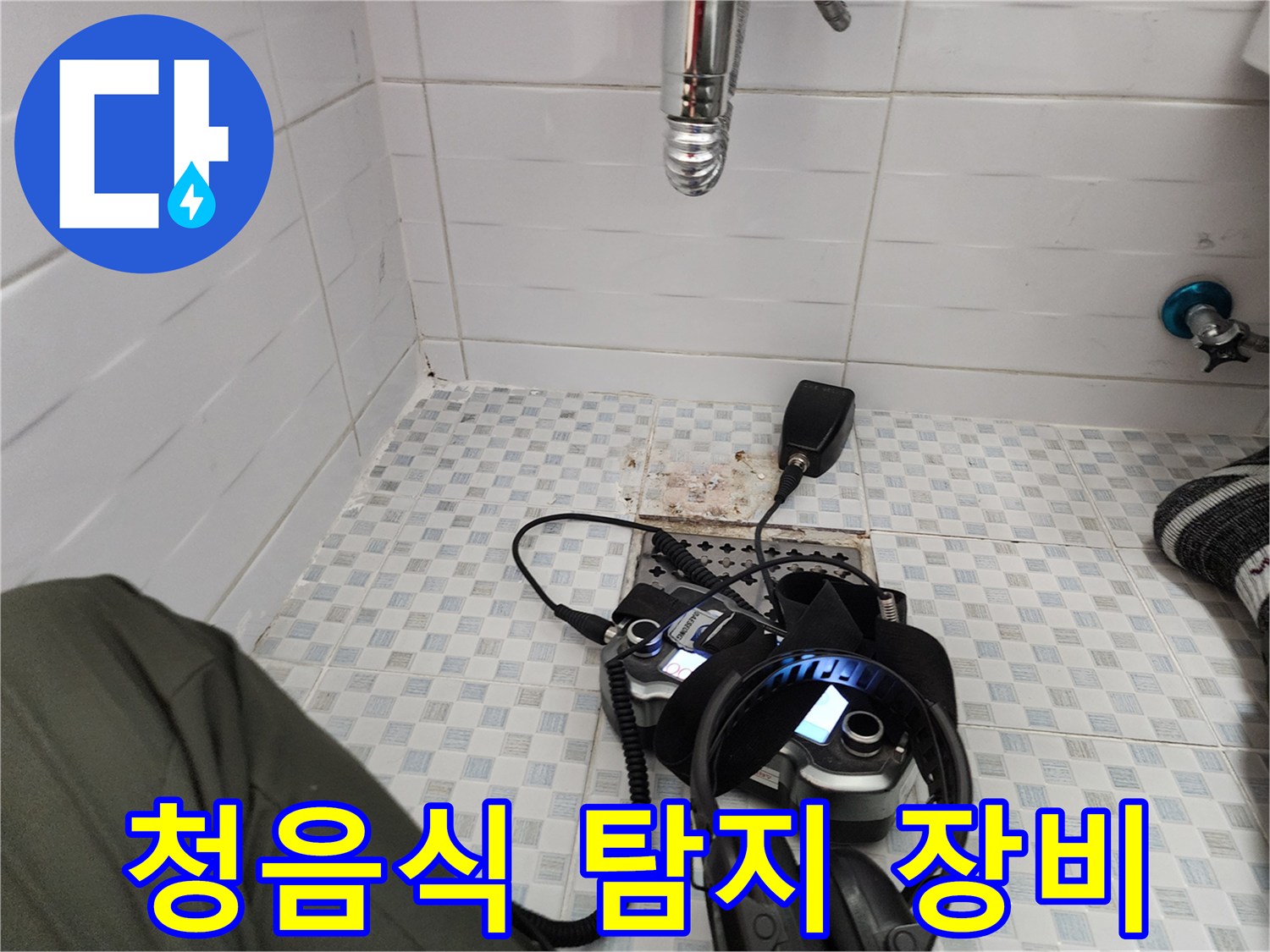 화장실 바닥에 놓인 청음식 탐지기와 헤드셋-배관 누수음을 듣기 위한 정밀 진단 도구입니다.