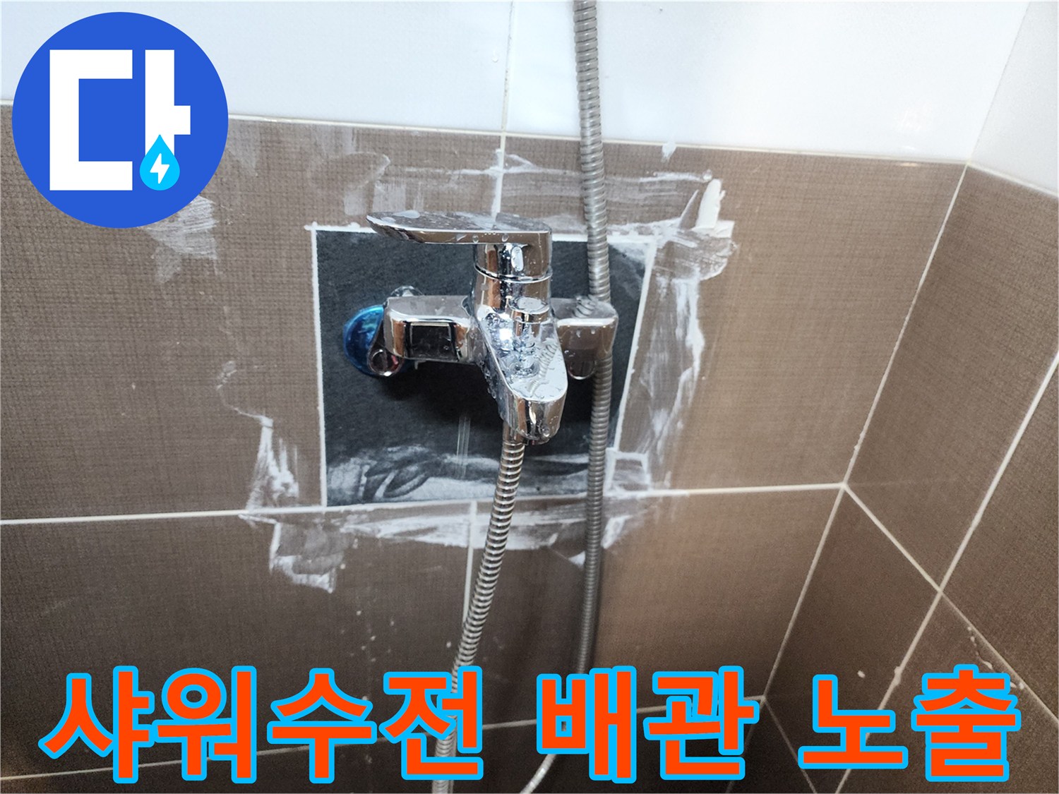 욕실 벽면 샤워 수전 주변의 타일이 제거되어 배관 상태가 드러난 모습입니다.