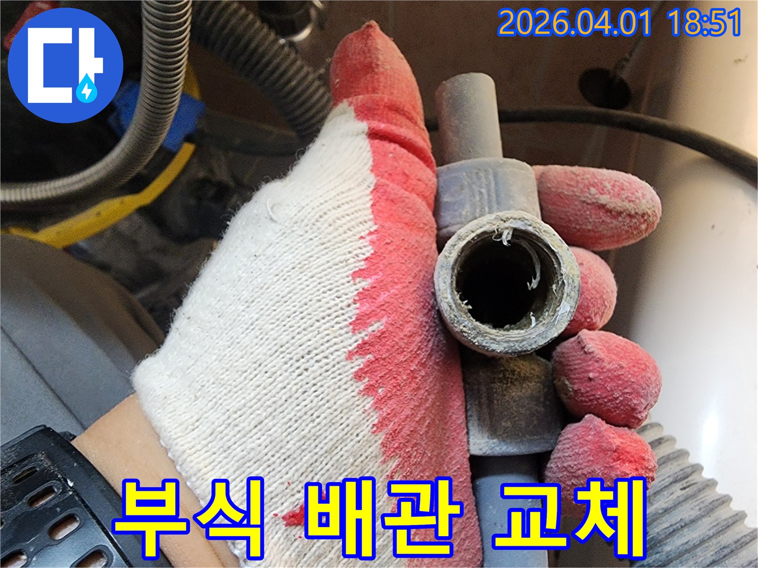 작업용 장갑을 낀 손으로-심하게 부식된 배관을 들고-교체 작업의 필요성을 설명하는 모습