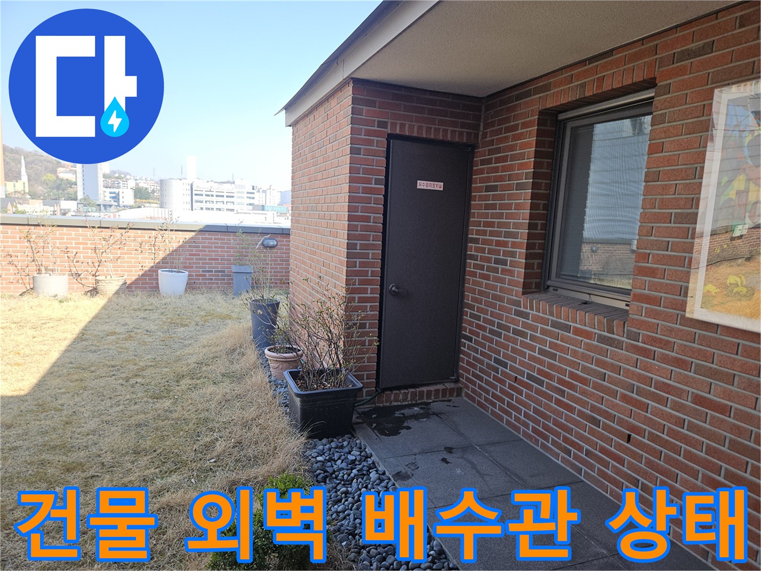 붉은 벽돌 외벽에 설치된 배수 시설과 주변 마감을 보여주는 사진입니다.