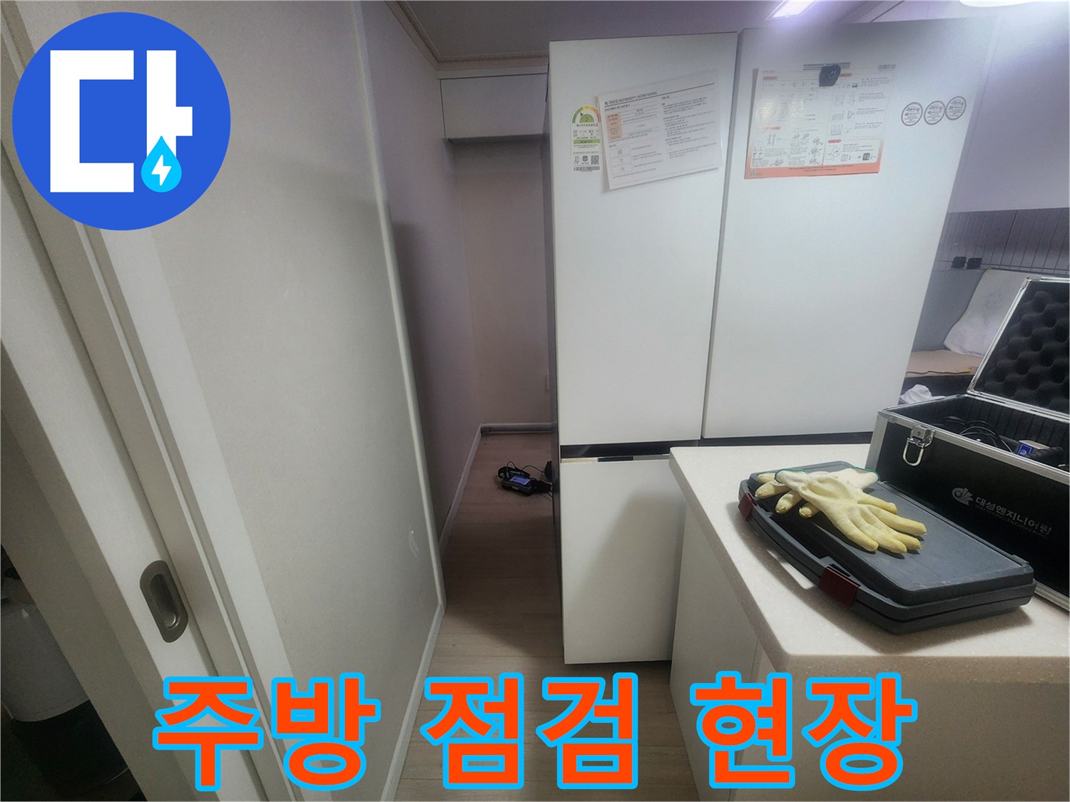 주방 냉장고 옆에 준비된 누수 탐지 장비와 작업용 장갑