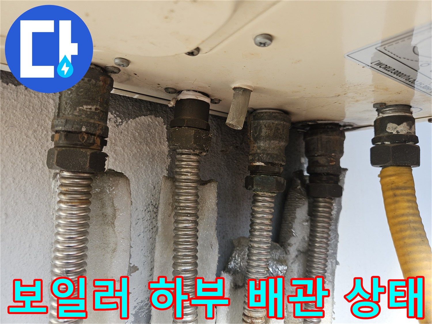 보일러 아래쪽 연결된 은색 주름관과 노란색 호스 모습