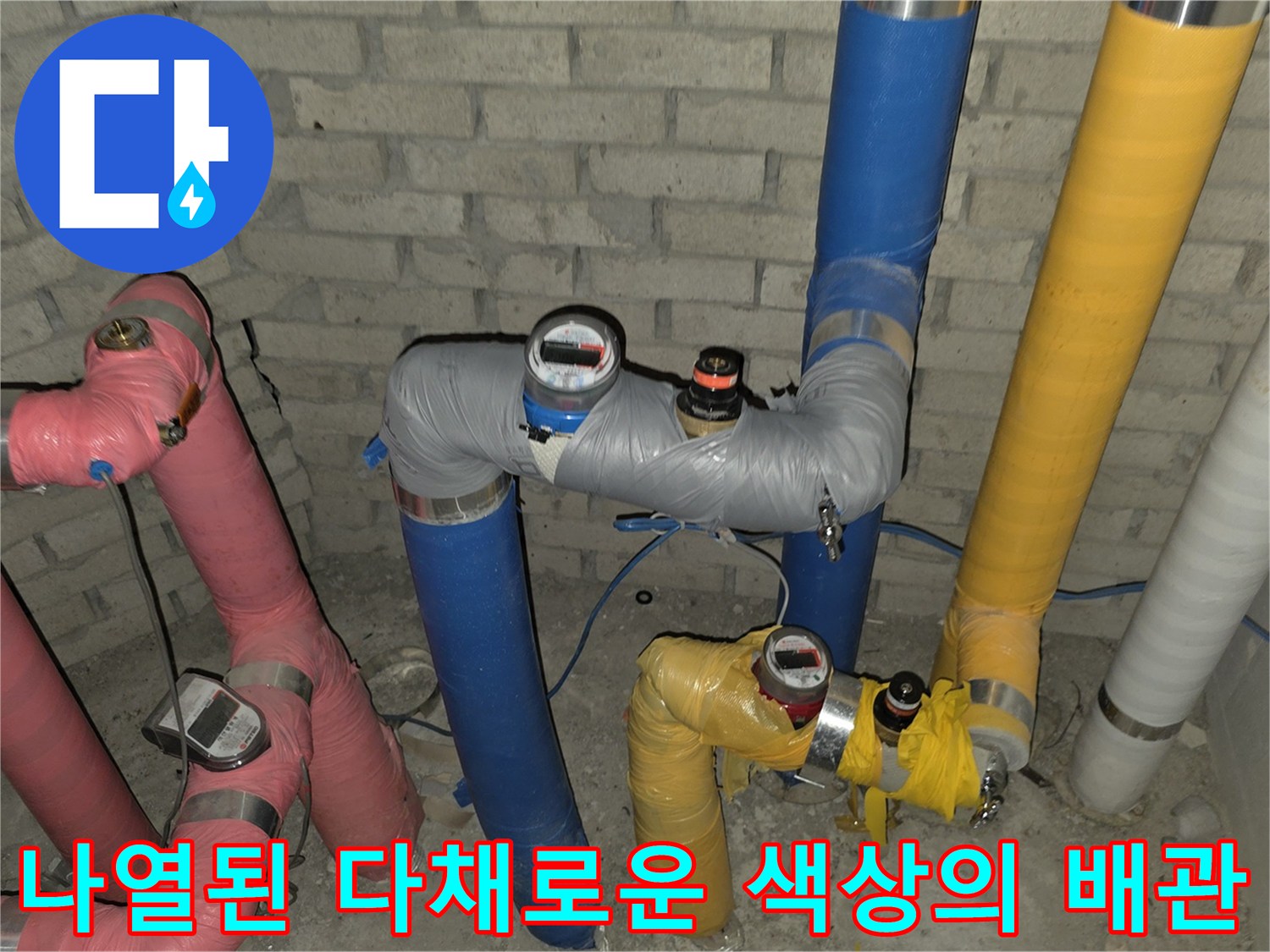 벽면에 나란히 배치된 분홍색과 파란색 및 노란색 배관들의 모습