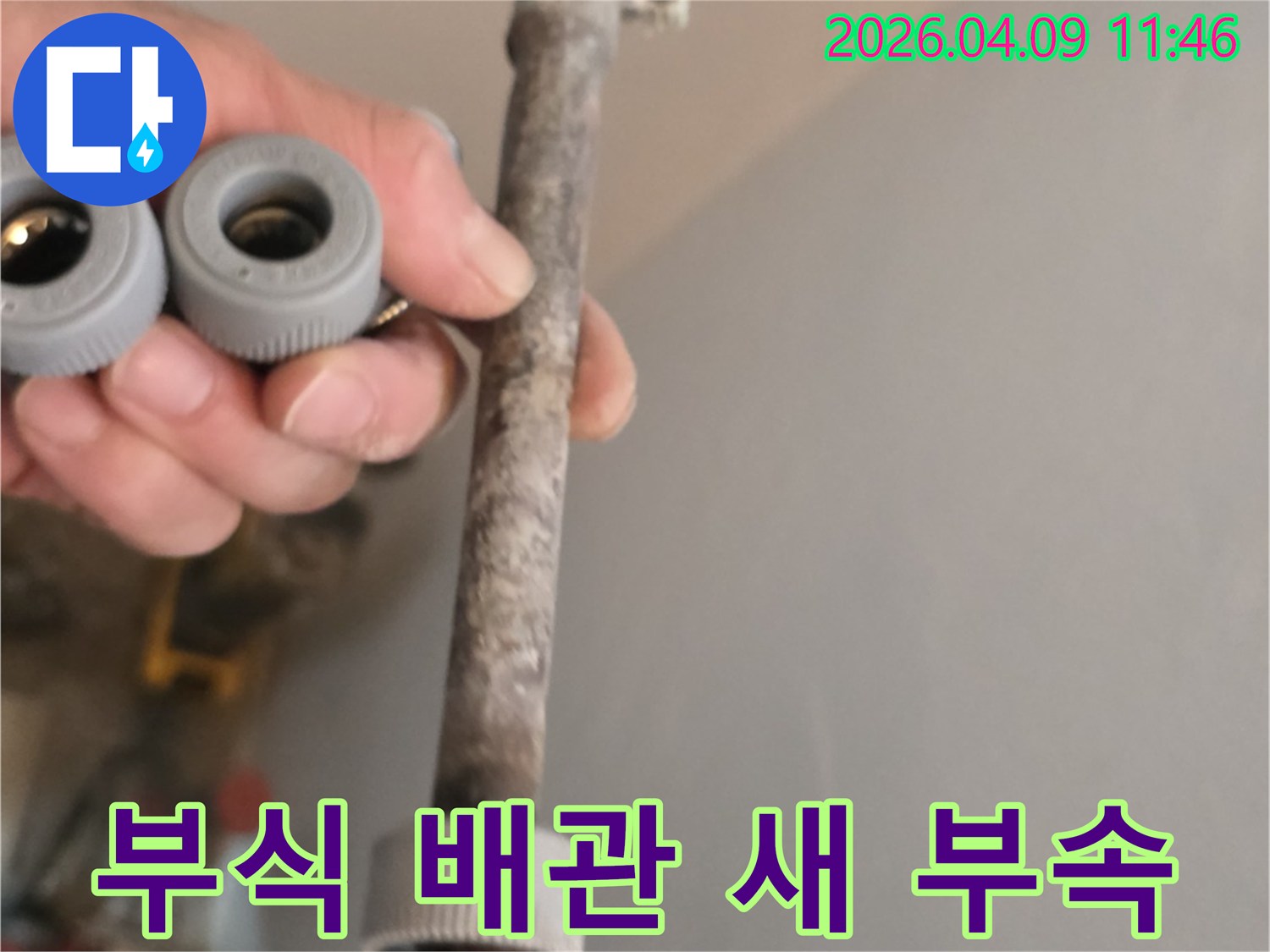 이 사진은-오랜 사용으로 부식된 수도관과-새롭게 교체할 배관 부품을-함께 보여주고 있습니다