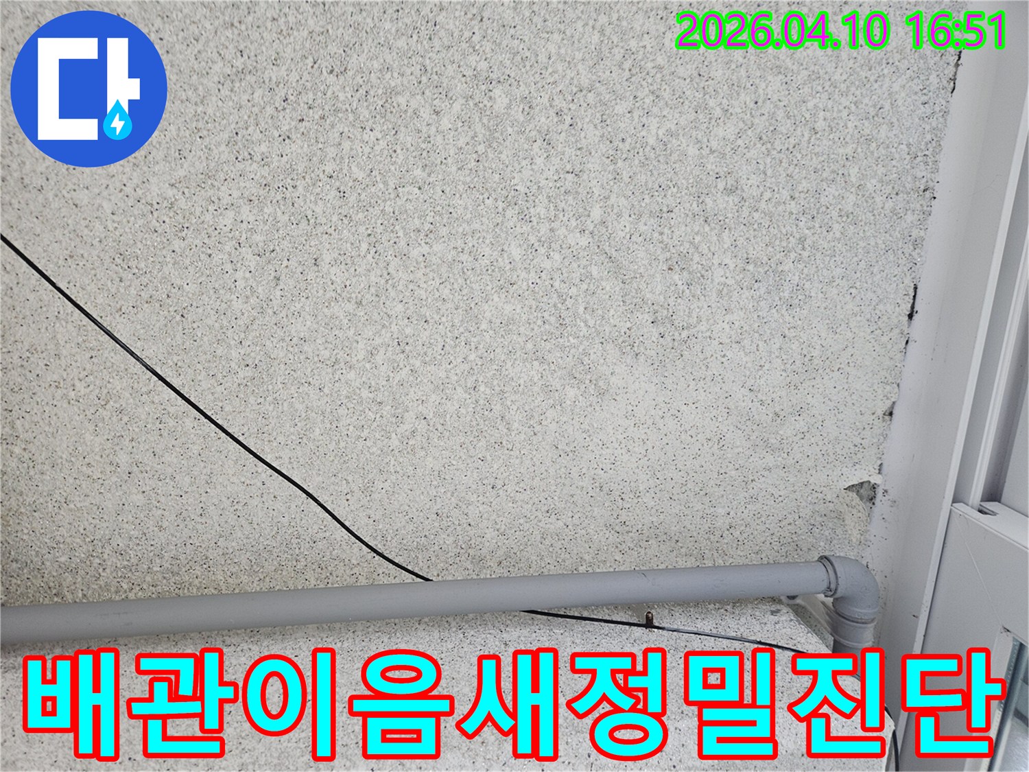 회색 벽면의-회색 배관과-검은 전선이-누수 진단을 위해-배관의 이음새 부분을-정밀하게-점검하는 모습입니다