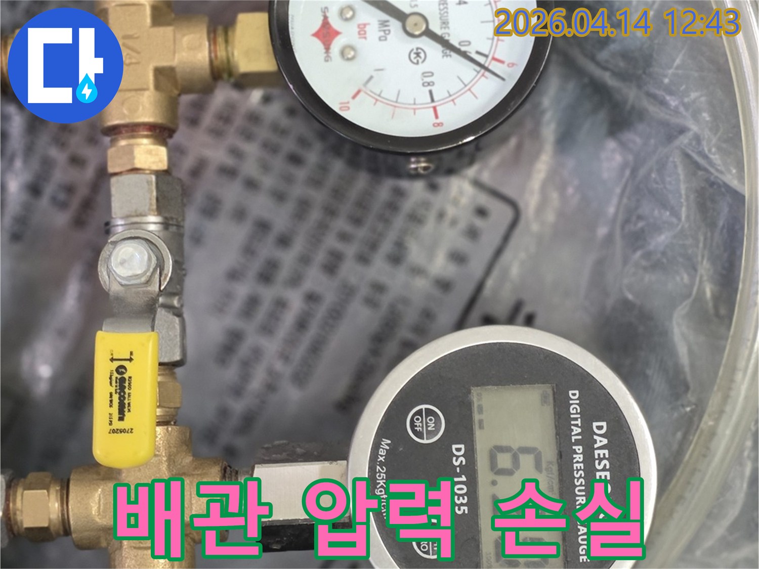 누수 탐지 전문 장비인 압력 게이지가 배관에 연결되어 압력 변화를 측정하고 있습니다.
