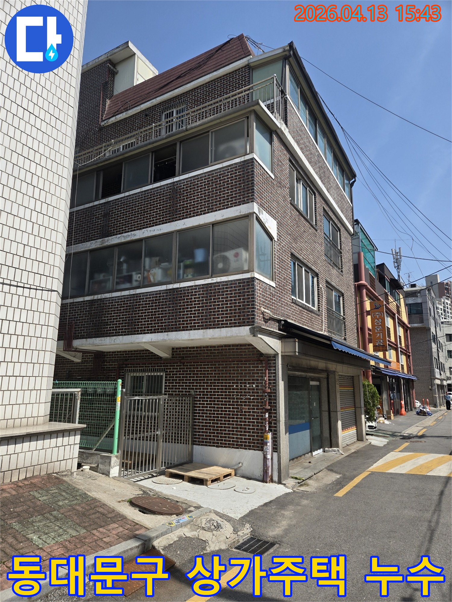 동대문구의-상가주택-건물-외관을-보여주는-이-사진은-지하층-침수-문제로-인한-누수-원인을-찾기-위해-전문-엔지니어가-현장을-점검하는-모습입니다.