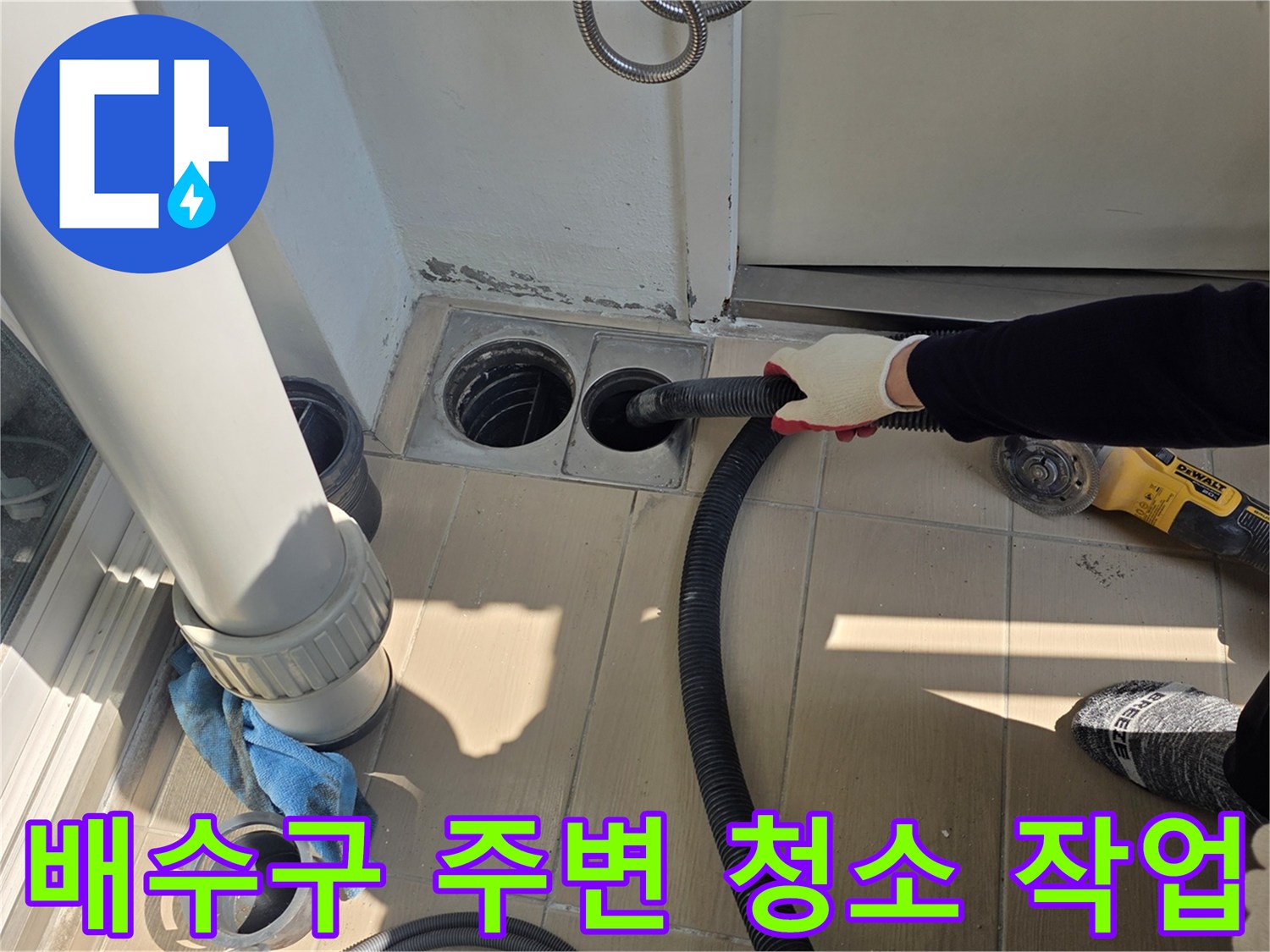 배수구 주변의 이물질을 제거하기 위해 진공청소기를 사용하는 모습