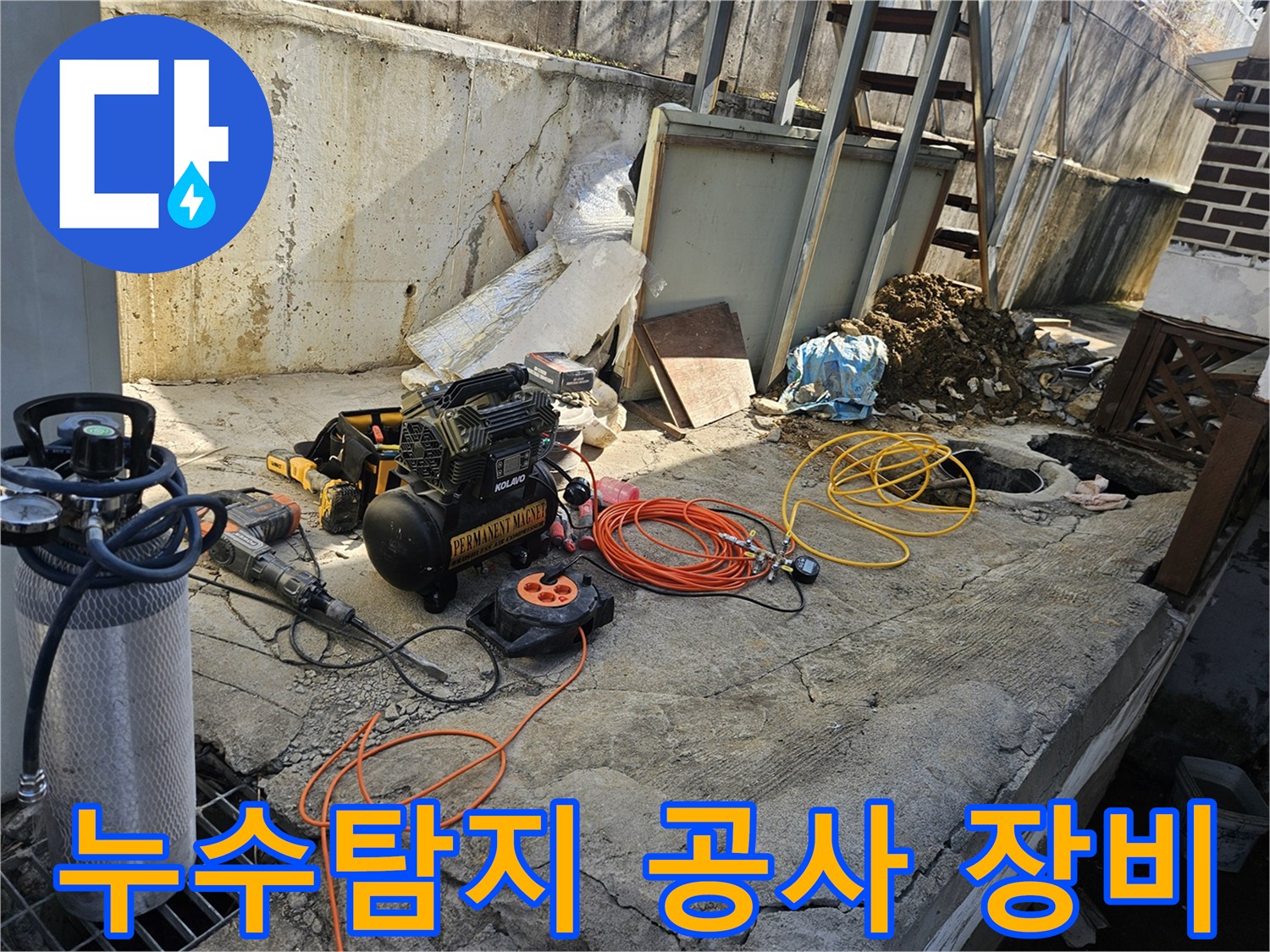 누수 공사 현장에서-에어 콤프레셔와-함마드릴-호스-전선릴 등-다양한 작업 도구들이-콘크리트 바닥 위에-준비되어 있는 모습