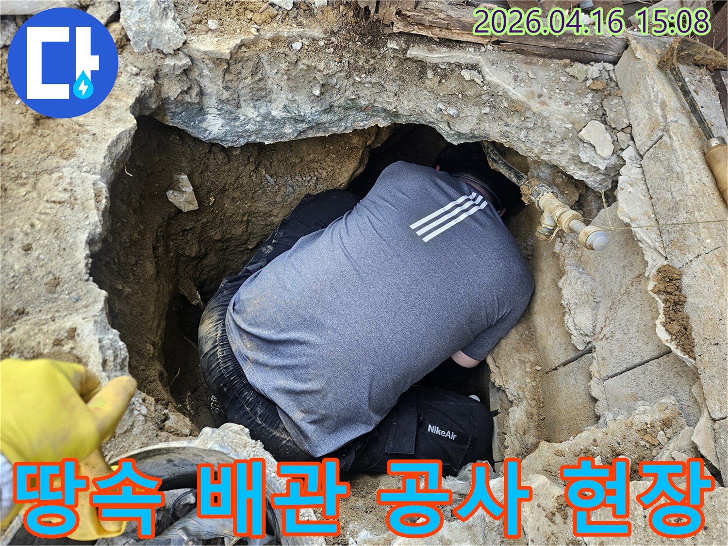 전문 배관 기술자가-땅속에 매설된 배관을-설치하거나 보수하기 위해-좁은 공간에서 작업하는 모습