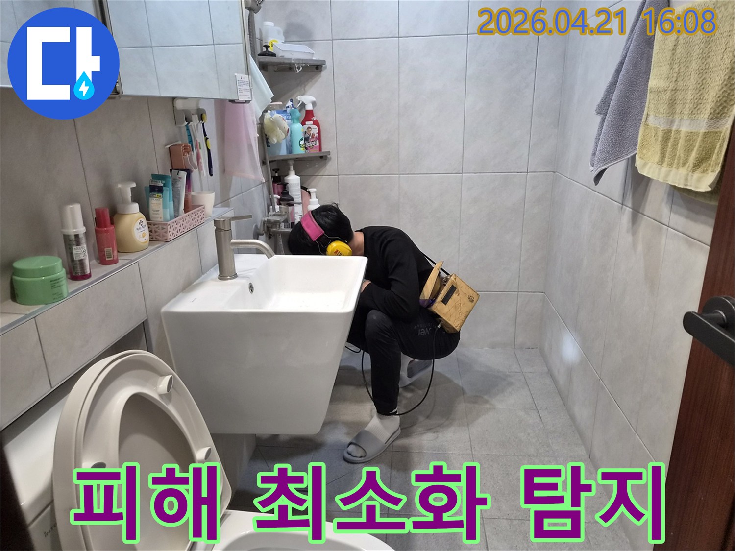 아파트 욕실에서 누수 탐지 전문가가-청음 장비를 이용해-배관의 미세한 누수음을 듣고-피해를 최소화하기 위해 누수 지점을 찾아내고 있습니다
